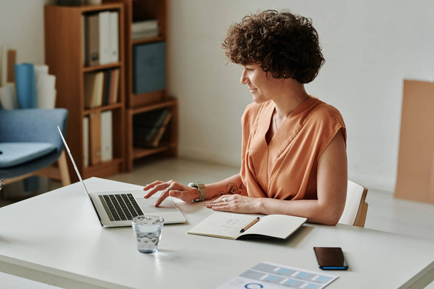 Junge Geschäftsfrau nutzt Laptop für Online-Arbeit an ihrem Arbeitsplatz im Büro - Foto, Bild