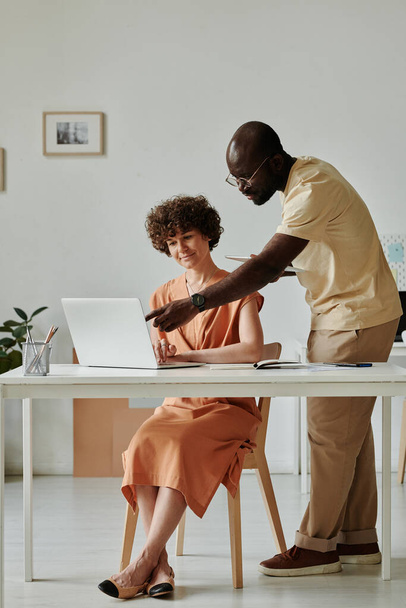 Африканский бизнесмен указывает на монитор ноутбука и обсуждает онлайн-проект со своим коллегой - Фото, изображение