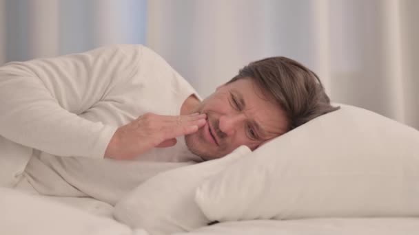 volwassen volwassen man met tandpijn liggend in bed op kant - Video