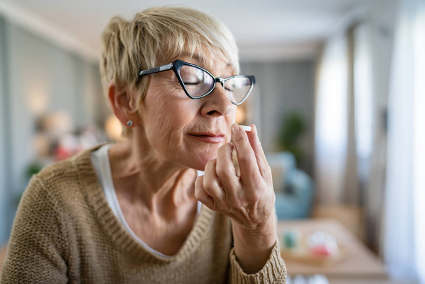 Eine ältere kaukasische Frau alte Frauen nehmen Medikamente oder ergänzen Vitamin-Brausetabletten Geruch zu Hause echte Menschen Gesundheitskonzept - Foto, Bild