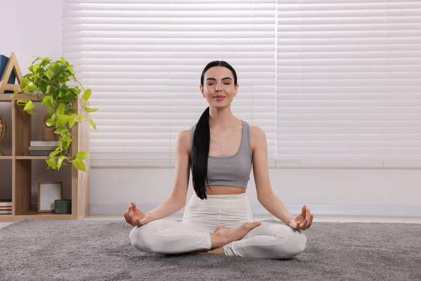 Donna in abbigliamento sportivo che medita a casa. Armonia e zen - Foto, immagini