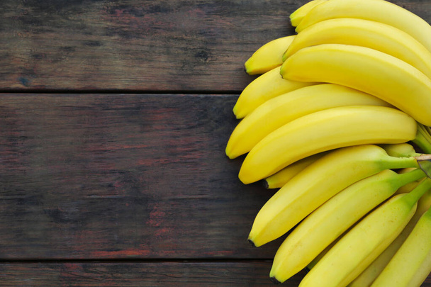 Ripe yellow bananas on wooden table, flat lay. Space for text - Foto, Bild