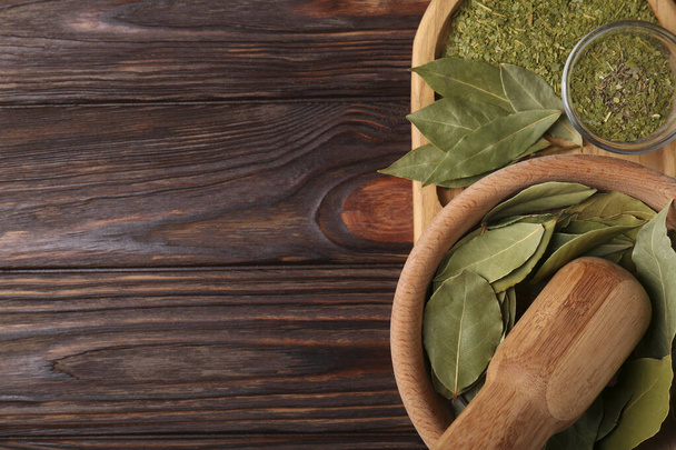 Whole and ground bay leaves on wooden table, top view. Space for text - Фото, зображення