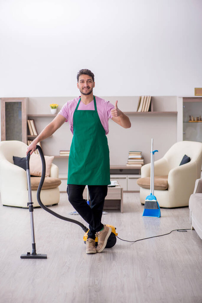 Young contractor cleaning the house - Foto, afbeelding