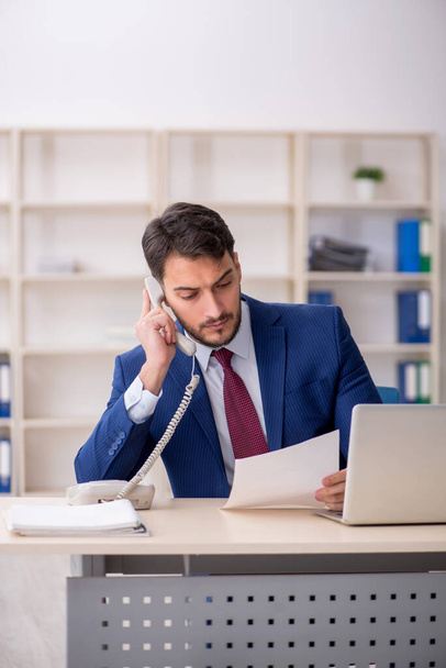 Young employee speaking by phone at workplace - Photo, Image