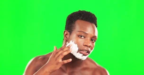 Zwarte man, gezicht en crème te scheren op groen scherm, verzorging en hygiëne met schoonheid op studio-achtergrond. Portret, huidverzorging en gezichtshaar verwijderen met serieuze mannelijke, mockup ruimte en dermatologie. - Video