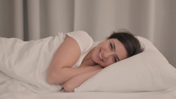 Boční pohled na mladou ženu pomocí Smartphone zatímco sedí na lokti v posteli - Záběry, video