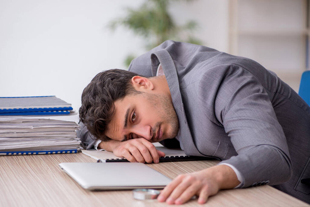 Young employee and too much work at workplace - Photo, image