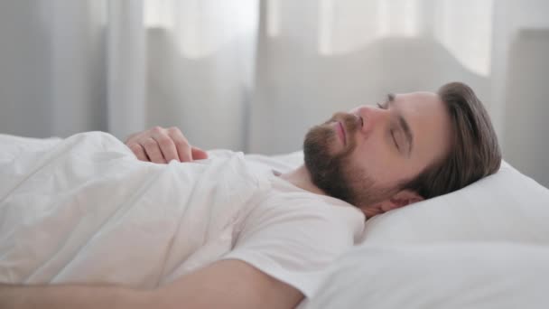Boční pohled na mladého dospělého muže spí v posteli - Záběry, video