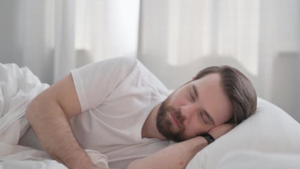 Fiatal felnőtt férfi alszik az ágyban az oldalon - Felvétel, videó