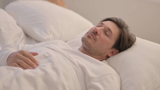 Moe volwassen man slapen in bed thuis - Foto, afbeelding