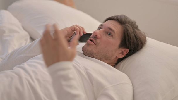 Upset Mature Adult Man Arguing on Phone in Bed - Foto, afbeelding