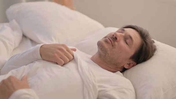 втомлений зрілий дорослий чоловік лежить в ліжку спати
 - Фото, зображення