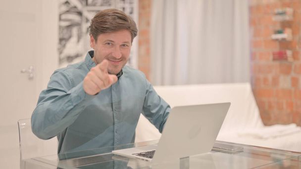 Ja, volwassen volwassen man wijzend vinger tijdens het werken op laptop - Foto, afbeelding