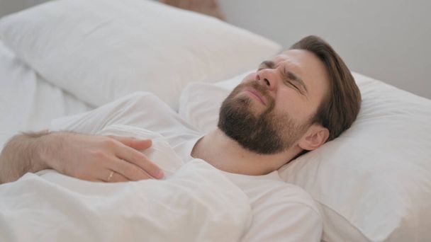 Jeune homme adulte inconfortable qui essaie de dormir au lit - Photo, image