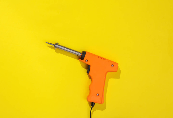 Soldering iron on a yellow bright background - 写真・画像