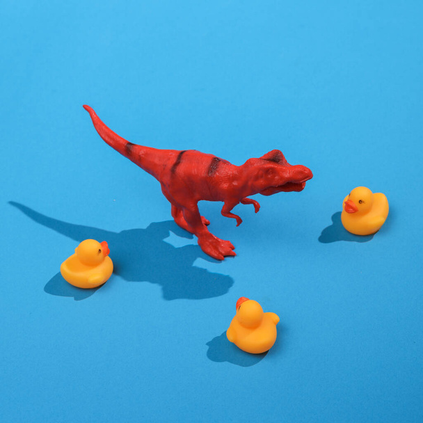 Creative layout with tyrannosaurus  and rubber ducks on bright blue background. Visual trend. Minimalistic aesthetic still life with shadow. Fresh idea - Foto, imagen