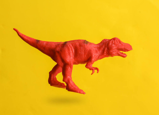 Plastic tyrannosaurus levitating on yellow background with shadow - Φωτογραφία, εικόνα