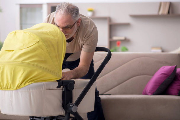 Ηλικιωμένος άντρας που φροντίζει νεογέννητα στο σπίτι - Φωτογραφία, εικόνα