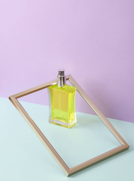 Cadre en or avec flacon de parfum sur fond pastel. Beauté minimale et mise en page de la mode - Photo, image