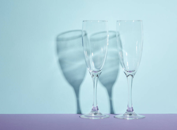 Creative layout with empty champagne glass on two tone pastel background. Visual trend. Minimalistic aesthetic still life. Reflection, shadows - Photo, Image