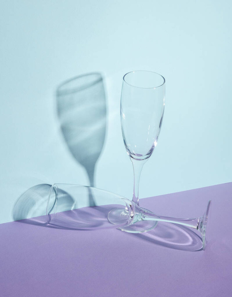 Creative layout with empty champagne glass on two tone pastel background. Visual trend. Minimalistic aesthetic still life. Reflection, shadows - Photo, Image