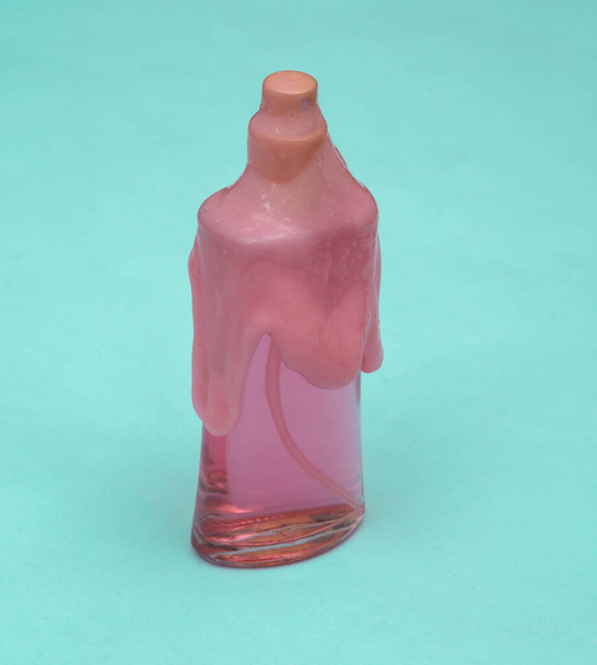 Creative beauty layout. Perfume bottle with pink slime on blue pastel background. Visual trend. Fresh idea - Photo, image