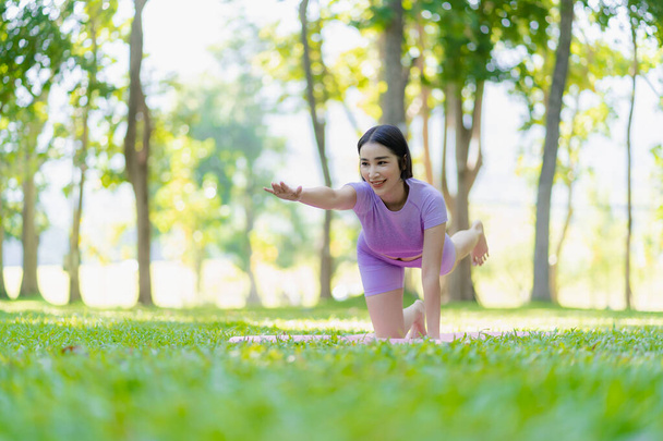 Giovane donna asiatica che fa yoga in giardino per l'esercizio e la buona salute. Nel parco asiatico fitness donna fare yoga e relax con abbigliamento sportivo nel parco verde in estate - Foto, immagini