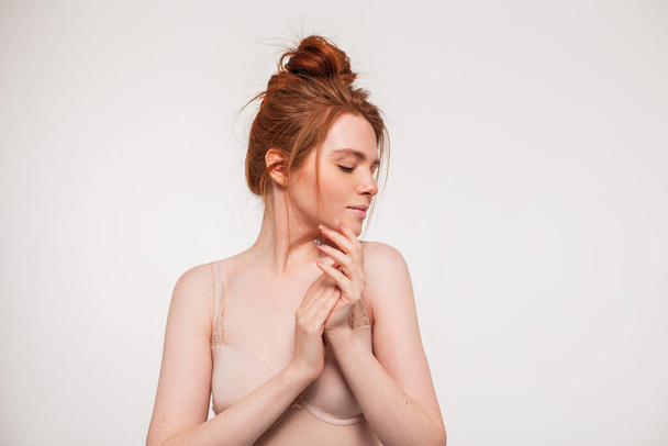 Young beautiful redhead fresh girl model with clean skin doing hand care and applying cream in the studio. Beauty, health and skin care - Valokuva, kuva