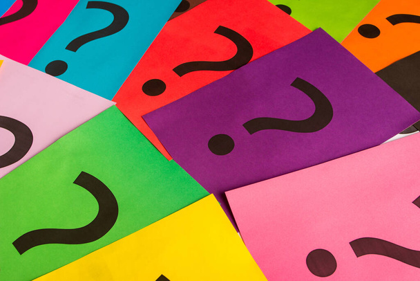 Black question marks on the colored papers, top view - 写真・画像