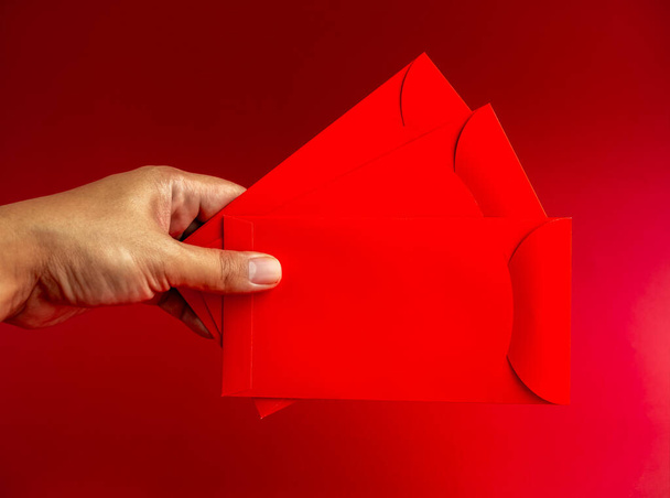 赤い背景に手で隔離された3つの赤い封筒。中国の旧正月、 1月の新年、結婚式の赤いパケットで幸運なお金の贈り物のための3 Hongbaoパケット. - 写真・画像