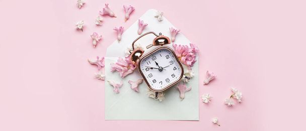 Alarm clock and spring flowers with envelope on pink background - Fotoğraf, Görsel