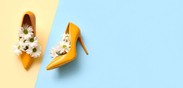 Pair of stylish high heeled shoes with flowers on color background with space for text - Photo, image