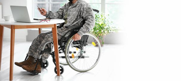 Солдат в инвалидной коляске работает дома. Баннер для дизайна - Фото, изображение