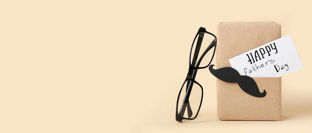 Glasses and gift for Father's Day celebration on beige background with space for text - Φωτογραφία, εικόνα