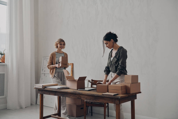 Due donne d'affari fiduciose che preparano i pacchi per la consegna in magazzino - Foto, immagini