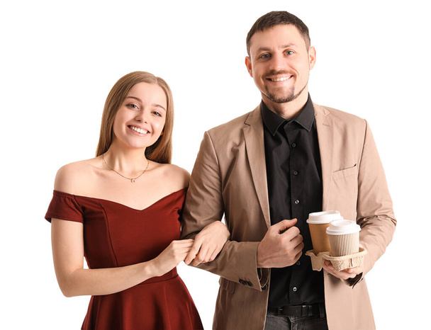Giovane coppia con tazze di caffè camminando mano nella mano su sfondo bianco - Foto, immagini