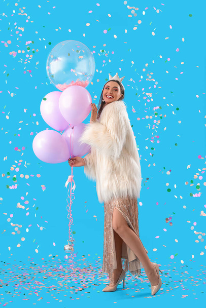 Beautiful woman with Birthday balloons and confetti on blue background - Photo, Image
