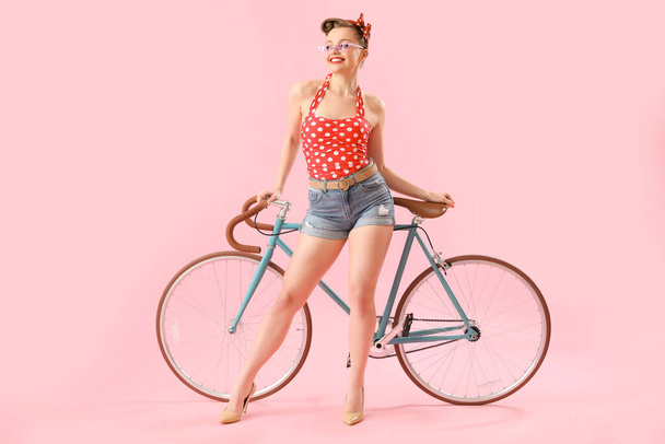 Young pin-up woman with bicycle on pink background - Fotografie, Obrázek
