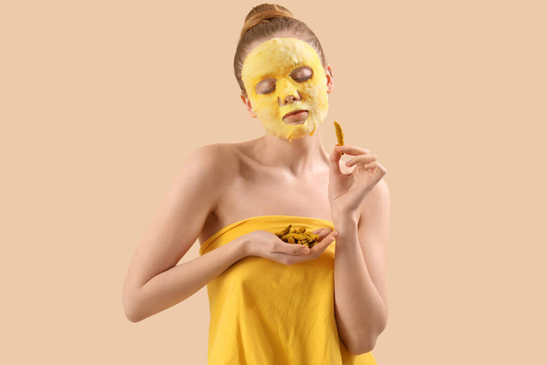 Young woman with turmeric sheet mask and roots on beige background - Foto, Bild