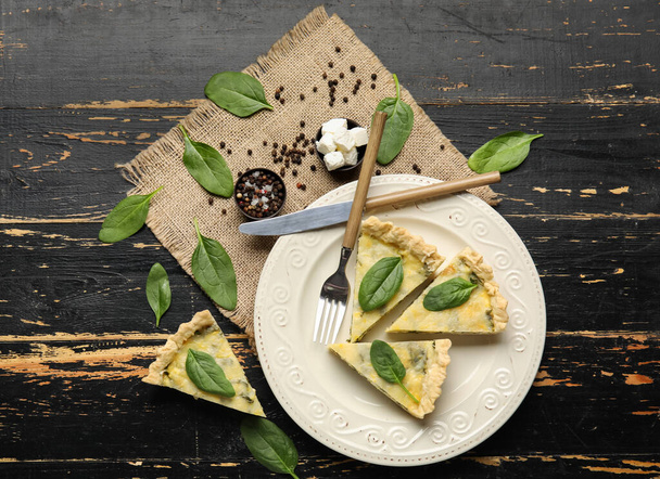 Plate with pieces of delicious quiche on black wooden background - Fotografie, Obrázek