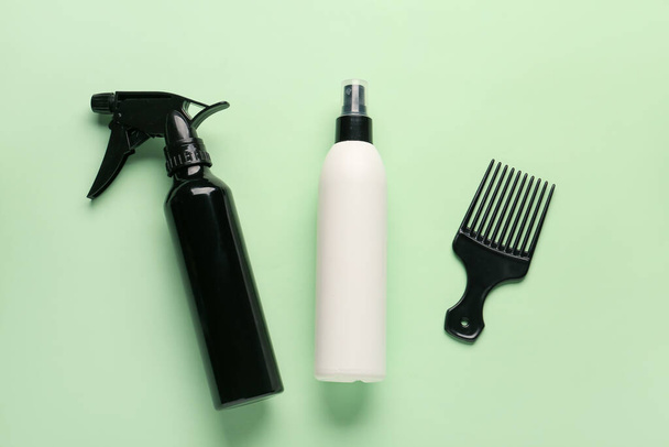 Bottles of hair sprays with comb on color background - Foto, imagen