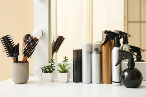 Different hair sprays and brushes on table in beauty salon - Fotoğraf, Görsel