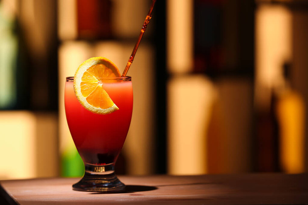 Glass of tasty Tequila Sunrise with orange slice on table - Foto, imagen