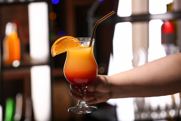 Femme tenant un verre de savoureuse Tequila Sunrise dans le bar - Photo, image