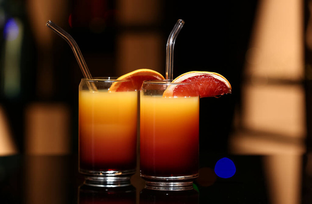 Glazen van smakelijke Tequila Sunrise op donkere tafel in bar - Foto, afbeelding