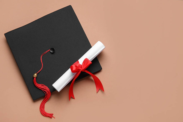 Δίπλωμα με κόκκινη κορδέλα και καπέλο αποφοίτησης σε καφέ φόντο - Φωτογραφία, εικόνα