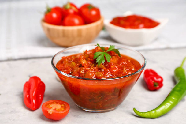 Bol de délicieuse sauce salsa sur table grunge grise, gros plan - Photo, image