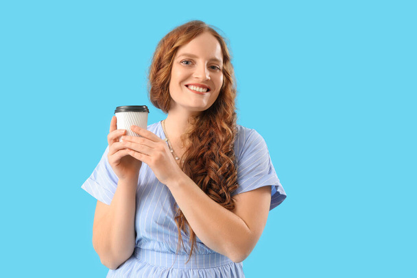 Kaunis punapää nainen kuppi kahvia sinisellä pohjalla - Valokuva, kuva