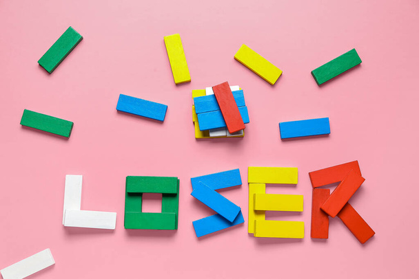 Λέξη LOOSER κατασκευασμένα από πολύχρωμα μπλοκ σε ροζ φόντο - Φωτογραφία, εικόνα
